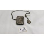 A silver vesta case on a silver watch chain with a silver fob, all silver except 'T' bar,