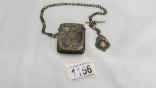 A silver vesta case on a silver watch chain with a silver fob, all silver except 'T' bar,