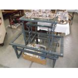 A set of 3 wrought iron coffee tables with glass tops.