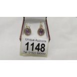 A pair of amethyst set pendant earrings in yellow metal.