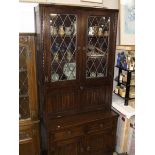 A dark oak dresser with leaded glass doors and linen drape carved doors