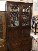 A dark oak dresser with leaded glass doors and linen drape carved doors