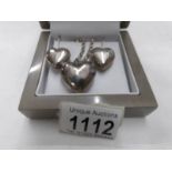 A silver heart pendant with matching earrings.