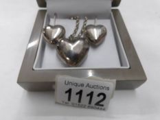 A silver heart pendant with matching earrings.