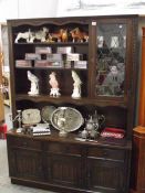 A dark oak dresser with leaded glasss door and linen fold carved doors