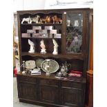 A dark oak dresser with leaded glasss door and linen fold carved doors