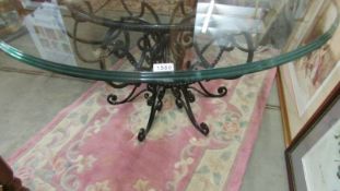 A wrought iron based table with glass top.