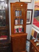 A dark wood stained corner cupboard with glazed door