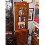 A dark wood stained corner cupboard with glazed door