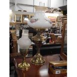 A brass oil lamp with floral glass shade and a brass candle lamp.