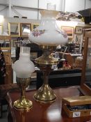 A brass oil lamp with floral glass shade and a brass candle lamp.