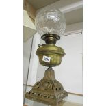 A Victorian oil lamp with brass font on cast iron base with burner and shade but missing chimney.