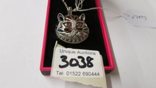 A silver and enamel Louis Wain style cat pendant necklace with ruby eyes.