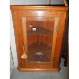 An oak glazed hanging corner cupboard.