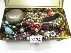 A tin of assorted costume jewellery.