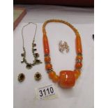 A matching necklace and earrings, a bakelite necklace and a gold coloured chain necklace with stone.