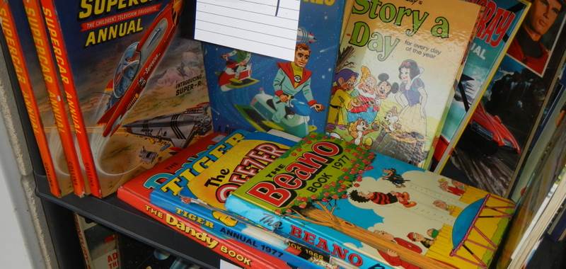 A shelf of assorted annuals including Beano, Dandy, Tiger, Super Car etc.