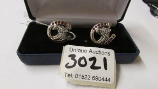 A pair of silver cuff links in the form of horse shoes set with rubilites.