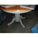 A circular kitchen table on painted base.