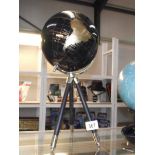 A black globe with gold mapping on a tripod base.