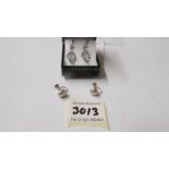 A pair of silver pendant earrings and a pair of silver screw earrings.