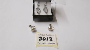 A pair of silver pendant earrings and a pair of silver screw earrings.