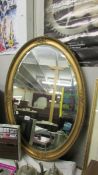 An oval bevel edged mirror in gilt frame.