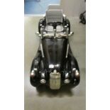 A vintage style battery powered children's black open top sports car. Approximately 120cm long.