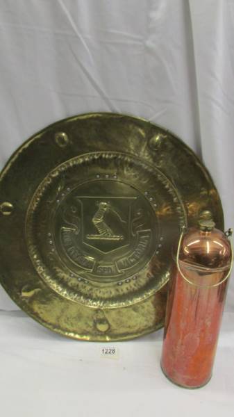 An Army & Navy stores copper flask and a large brass wall plaque depicting a coat of arms.