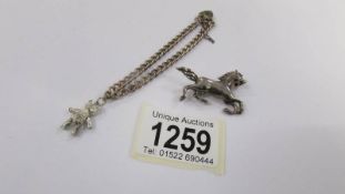 A silver bracelet and a silver horse brooch.