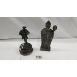 A bronze sculpture of a Tudor man and a stone plaque of a holy man.