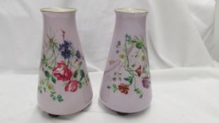 A pair of possibly French porcelain bases on three feet in lilac and decorated with flowers and