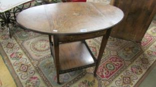 An oval inlaid drop side table on castors (central inlay a/f).