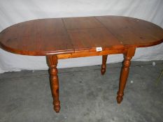 An oval teak extending table, 127 cm (open), 110 cm (closed) x 80 x 74 cm.