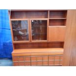 A large teak wall unit with 3 doors to base, 3 drawers and glass fronted cupboards, lit.