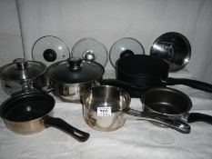 A mixed lot of clean saucepans, some with lids and some spare lids.