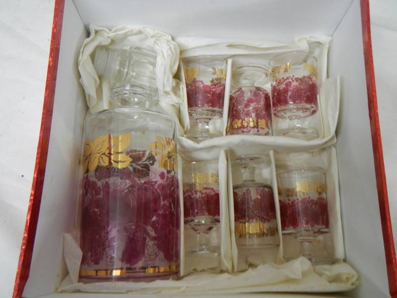 A mid 20th century boxed decanter and glass set decorated with red and gold transfers. - Image 3 of 4