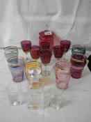 2 good sets of coloured glasses, a cranberry glass lidded jar, an etched decanter and 2 glasses.