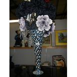 A tall black vase with coloured mirror and floral decoration.