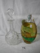 An early 20th century cut glass decanter and an unopened bottle of alcohol.