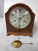 An 8 day mahogany inlaid mantel clock with key and pendulum.