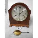 An 8 day mahogany inlaid mantel clock with key and pendulum.