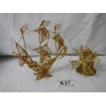 A gold coloured wire model of a sailing ship and a windmill.