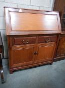 A teak bureau with 2 drawers and 2 cupboards.