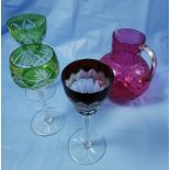 3 early 20thC coloured glass tall stem Wine Glasses (2 green, 1 red) & a cranberry glass Jug (chip