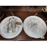Pair of Porcelain Wall Plaques, circular, with raised portraits “by the fire” (damaged fingers) &