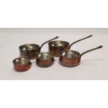 Set of five graduated copper and metal saucepans.