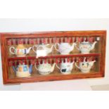 Eight tea pots in display cabinet.