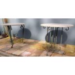 Two wrought iron garden tables with circular marble tops.
