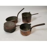 Collection of four copper and brass saucepans and a colander.